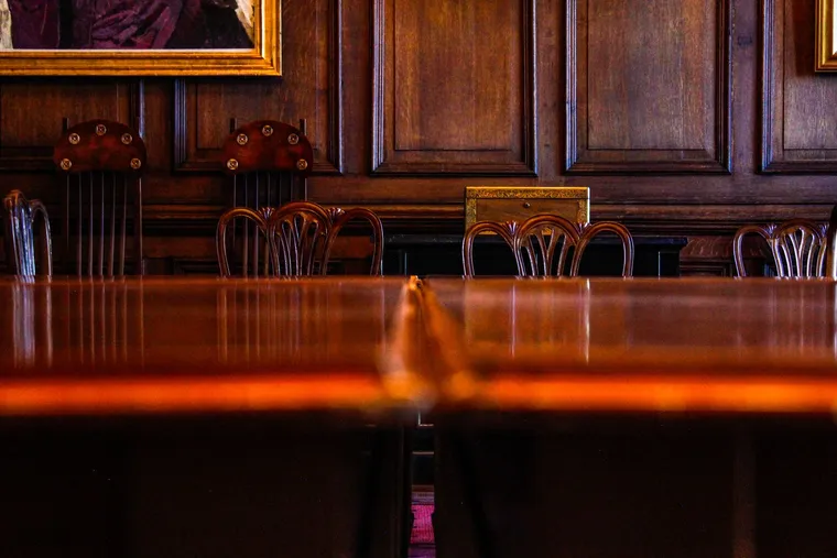 An oak-paneled boardroom with antique chairs and a polished conference table