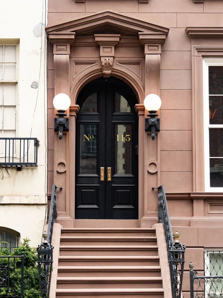 An elegant brownstone entrance with a black door and brass fixtures