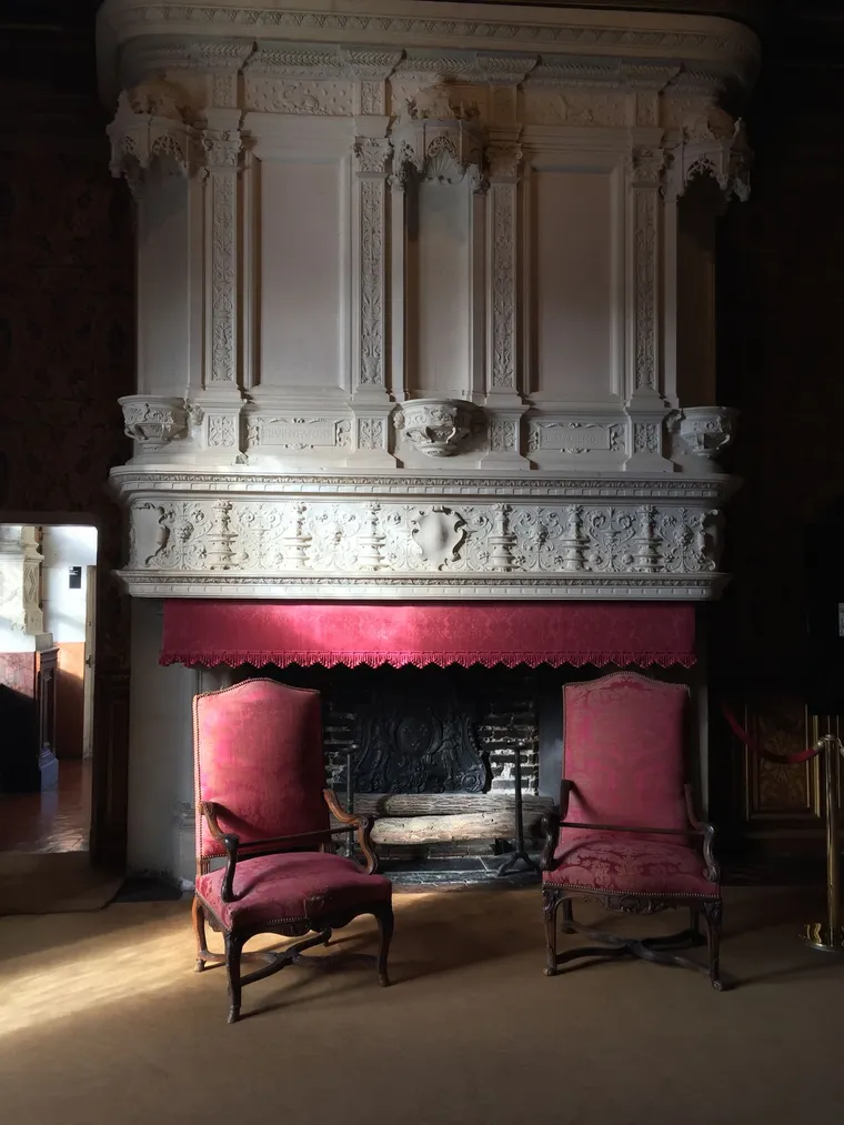 Two antique armchairs facing each other beside a carved stone fireplace