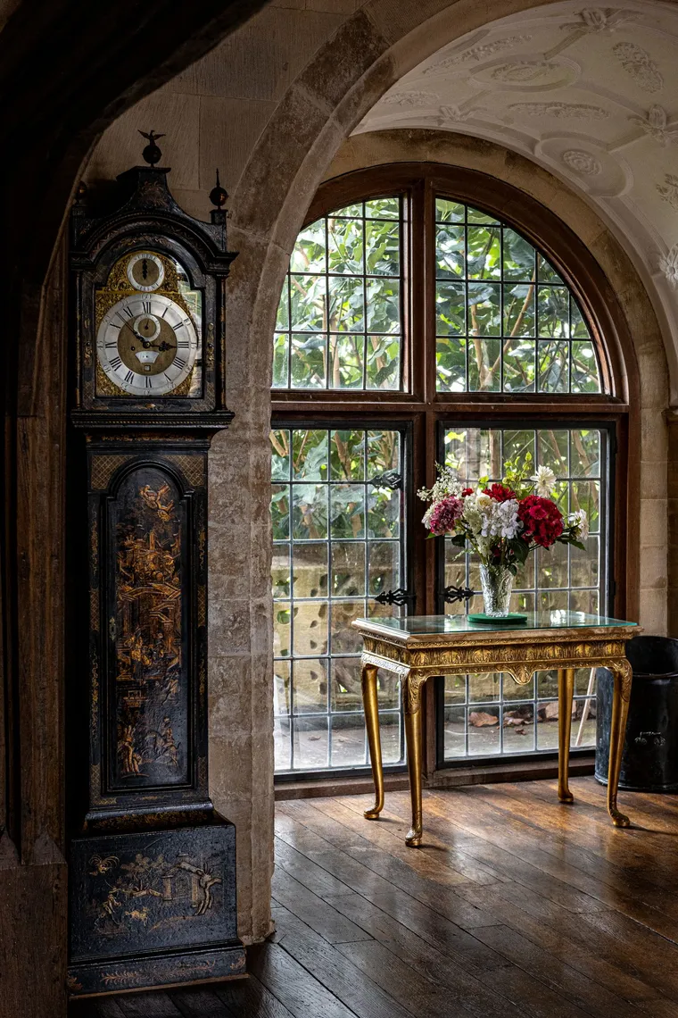 An antique grandfather clock and gilded table in a grand hallway